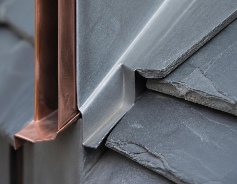 Nahaufnahme eines gekanteten Metallanschlusses am Übergang zur Schieferdachfläche