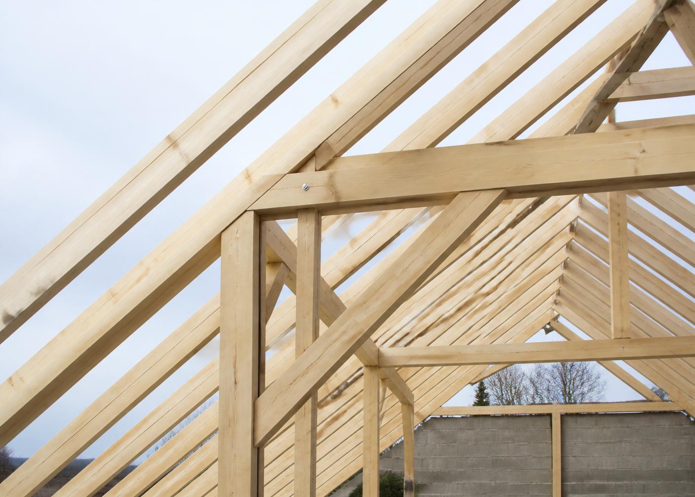 Neu errichteter Holzdachstuhl mit präzisen Zimmermannsverbindungen vor hellem Himmel