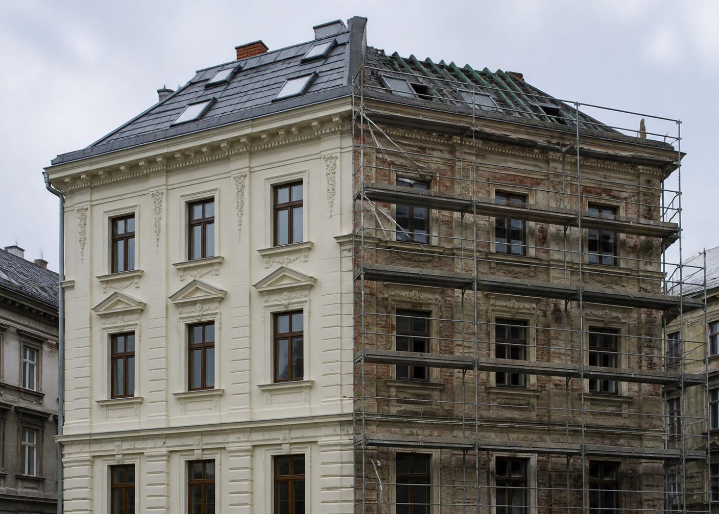 Altbau in Sanierung: eine Gebäudehälfte bereits mit neuem Dach und Putz, die andere eingerüstet